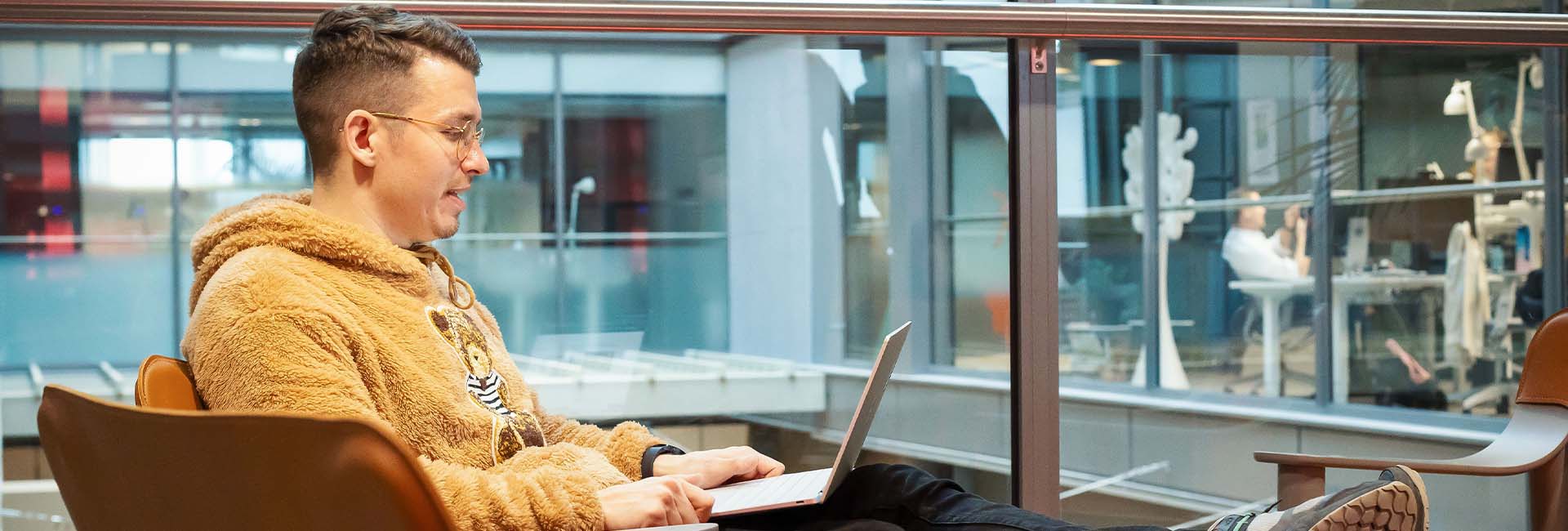 Henkilö opiskelee tekoälyverkkokurssia kannettavalla tietokoneella modernissa työympäristössä.