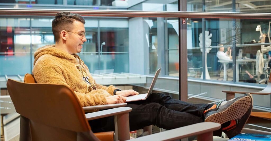 Henkilö opiskelee tekoälyverkkokurssia kannettavalla tietokoneella modernissa toimistoympäristössä.