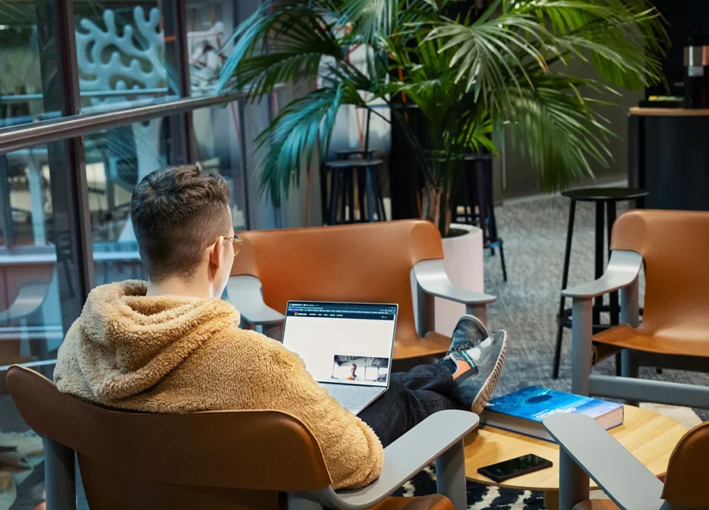 Henkilö suorittaa tekoälyverkkokurssia kannettavalla tietokoneella viihtyisässä työtilassa.